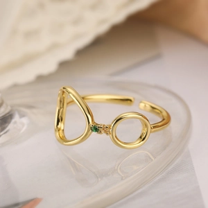Detailed view of adjustable gold ring with pear and circular emerald-colored zircon stones