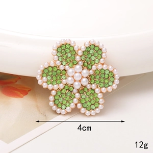 Vue détaillée d'une broche tournesol de 4cm avec strass verts et perles blanches