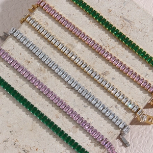 Macro detail of 18K gold plated bracelets with radiant cut zircon in green and pink colors