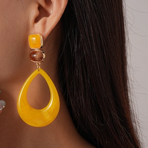 Close-up of model wearing yellow teardrop resin earrings with marbled texture detail