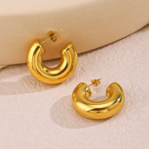Polished 18K gold plated hollow C-shaped hoop earrings on a minimalist textured surface