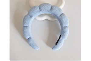 Close-up of soft light blue cloud sponge headband with plush texture on white background