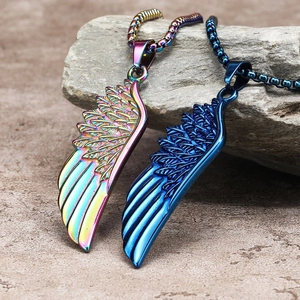 Macro view of rainbow and blue stainless steel wing pendants on a natural rock