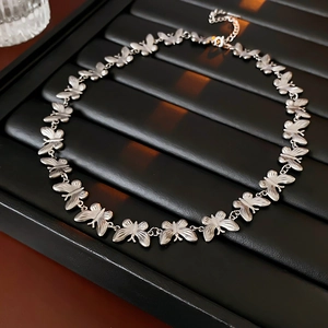 Macro view of silver butterfly link necklace on black wave display tray