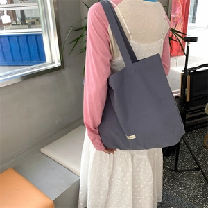 Gray canvas tote bag showing size scale and drape on shoulder from a side-back view