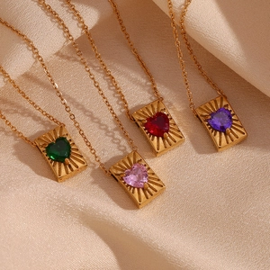 Detailed view of colorful heart zircon pendants on gold card necklaces over silk