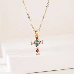 Détail du pendentif croix avec zircons colorés en forme de cœur sur chaîne en or