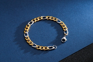 Detail of two-tone gold and silver Figaro chain bracelet with lobster clasp on blue fabric