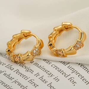 Gold plated bamboo zircon hoop earrings shown on aesthetic book and fabric background