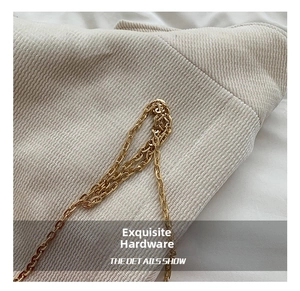 Detailed close-up of high-quality gold metal chain and cream corduroy fabric texture