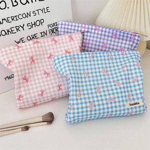 Dettaglio di tre trousse da trucco a quadretti con fiocchi rosa e chiusura a zip