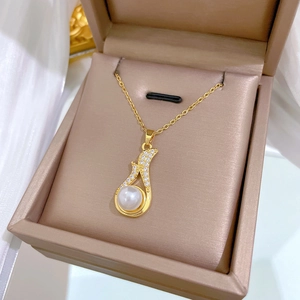 Macro view of gold pendant with white pearl and sparkling crystals in a gift box