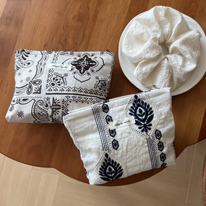 Linen pouch set with ethnic patterns and white lace scrunchie on wooden table
