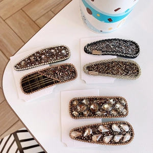 Detail of six sparkling rhinestone hair clips in gold and brown on a white surface