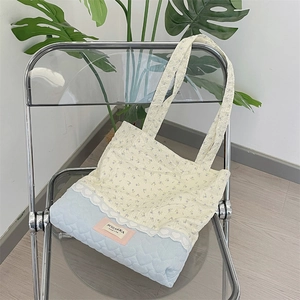 Detail of floral and heart quilted tote bag with lace trim on a stylish chair