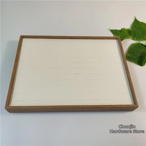 Detail of wooden jewelry tray with white velvet slots for rings and studs display