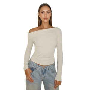 Haut moulant beige à épaules dénudées et manches longues avec un jean bleu délavé clair