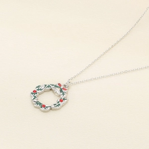 Detail of silver Christmas wreath pendant with red accents on a delicate steel chain