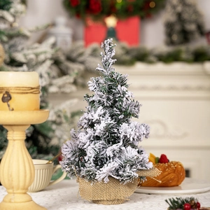 Mini tabletop Christmas tree with artificial snow and burlap base in warm home setting