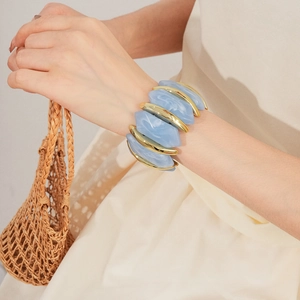 Gros plan de carreaux en acrylique marbré bleu clair sur un bracelet géométrique doré