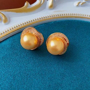 Macro shot of gold pearl earrings with wavy diamond-encrusted base and vintage texture