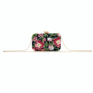 Close-up of vintage floral embroidery and gold crown clasp on an evening clutch bag