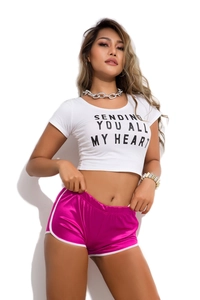 Detail of white crop top with heart text and magenta shiny athletic shorts on model