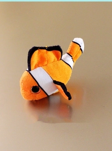 Macro shot of an orange plush clownfish magnet on a reflective surface