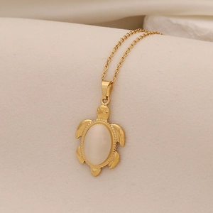 Close-up of a golden sea turtle pendant with a white opal stone on an O-chain necklace