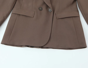 Détails du blazer marron à double boutonnage avec poches à rabat et texture de tissu lisse