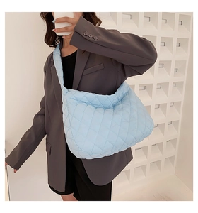 Close-up of quilted light blue puffy shoulder bag styled with a grey blazer outfit