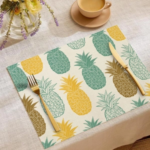 Detail of linen placemat with pineapple print, featuring gold cutlery in a home setting
