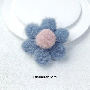 Detail of 6cm blue and pink plush flower accessory with soft texture on white plate