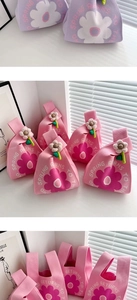 Detail of knitted wedding favor bags with 3D flower charms in pink and purple colors