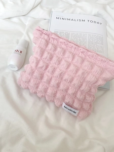 Pink bubble textured cosmetic bag with 'have a nice day' label in a minimalist setting
