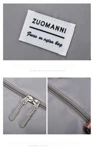 Detail of grey nylon sports bag showing dual metal zippers and stitched brand logo label