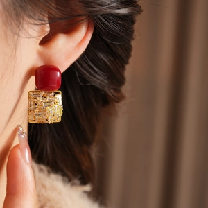 Close-up of model wearing burgundy resin and zircon square earrings in gold setting