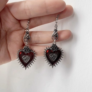 Detail of gothic silver bat earrings with red heart pendants and rose metal connectors