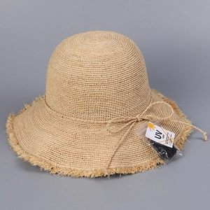 Detail of hand-woven straw hat showing raffia texture and UV care protection tag