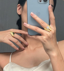 Close-up of elegant leaf-shaped gold rings with green and white zircon stones on model