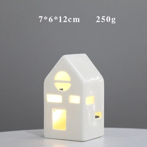 Detail view of a white ceramic house ornament with warm LED light and 7x6x12cm dimensions
