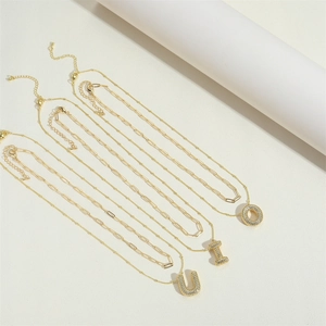 Close-up of three layered gold necklaces with zircon-encrusted letters U, L, and O