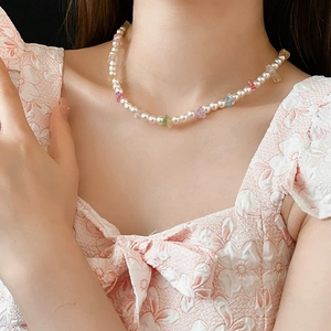 Detailed close-up of a pearl necklace with colorful irregular beads on a model neckline