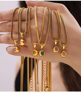 Macro detail of gold snake chains with spherical pendants featuring colorful zircons