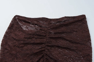 Close-up of deep brown lace fabric with mesh floral patterns and gathered pleats detail