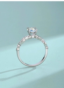 Close-up of Moissanite ring featuring a six-prong setting and leaf-shaped twisted band
