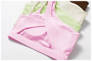 Detail of asymmetric one-shoulder sports bras showing four soft colors and high-elastic fabric