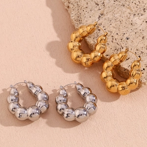 Chunky bubble textured gold and silver hollow hoop earrings on warm pink background