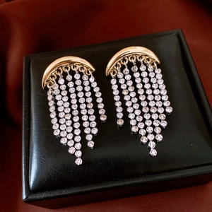 Vue détaillée des boucles d'oreilles croissant dorées avec franges de strass sur cuir noir