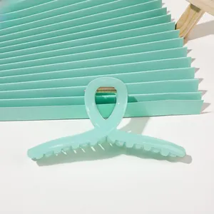 Close-up of mint green ribbon-shaped claw clip with durable gold metal spring